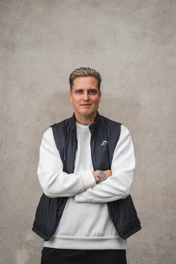 Mand i vest og sweatshirt med armene over kors